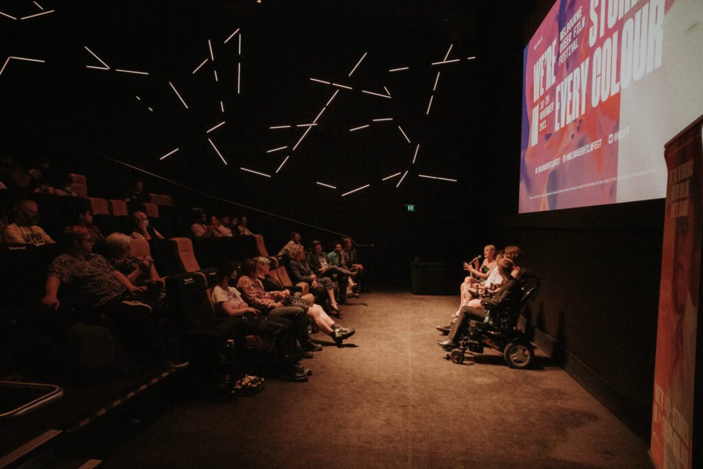 A cinema of movie-goers, with presenters under the screen