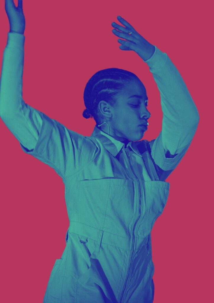 Young person frozen in a dance move; eyes closed and hands up in the air.